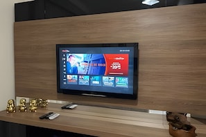 Uma televisão de tela plana fixada numa parede de madeira, com um balcão de recepção de madeira logo abaixo.