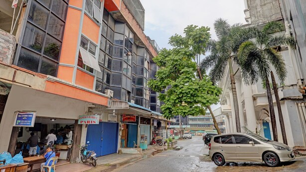 Vista callejera con un edificio que tiene una puerta azul y un letrero.