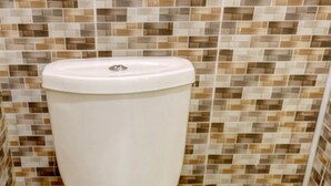 Un inodoro con asiento y tapa blancos, frente a una pared con azulejos de diseño geométrico.
