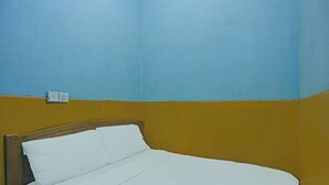 Una cama individual con ropa de cama blanca en una habitación con paredes amarillas y azules.