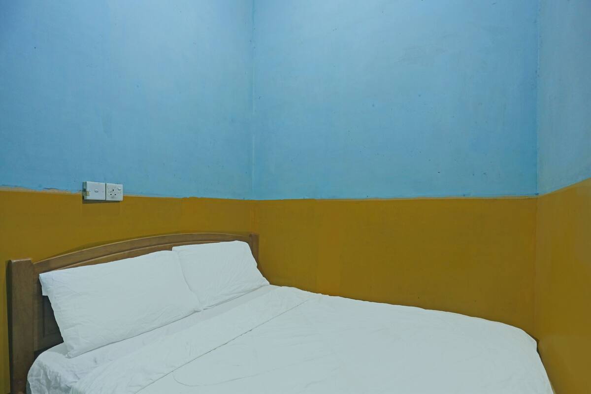 A single bed with white bedding in a room with yellow and blue walls.