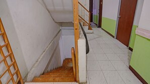 Una escalera estrecha con barandilla de madera y pasamanos metálico, que conduce a una plataforma.