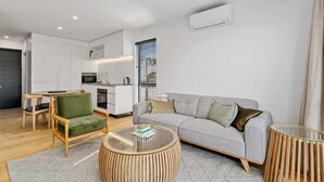 Un salon moderne avec un canapé gris, un fauteuil vert et une table basse ronde.