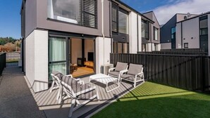 A modern two-story house with a patio area featuring outdoor furniture.