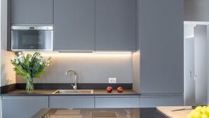 A modern kitchen with grey cabinets, a stainless steel oven, a sink, and a cutting board. - NEW! Design & Modern Flat in Trastevere (Roma)