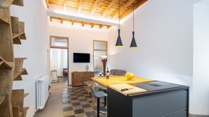 A modern kitchen with a wooden staircase, a dining area, and a TV mounted on the wall. - NEW! Design & Modern Flat in Trastevere (Roma)
