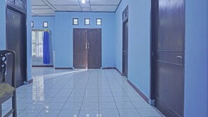 A hallway with tiled floors, blue walls, and wooden doors. - OYO 92997 Villa Hj Karnadi (Cisarua)