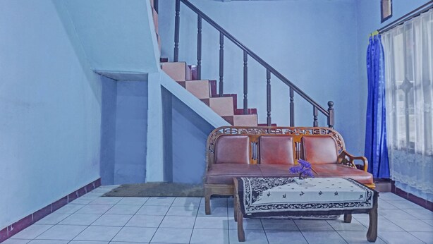 A living room with a sofa, a coffee table, and a staircase. - OYO 92997 Villa Hj Karnadi (Cisarua)