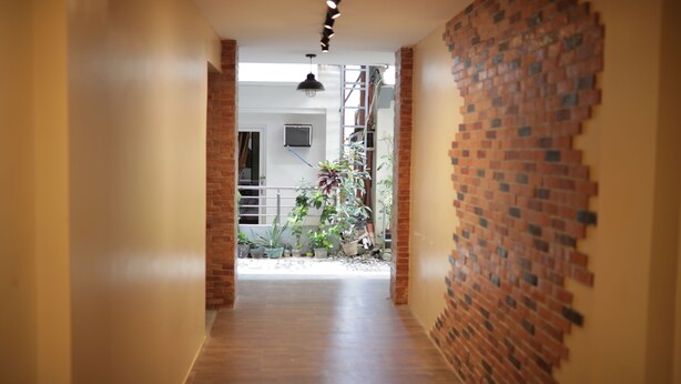 A hallway with a brick wall on the right, leading to a balcony with potted plants. - Cerca Hotel (Boracay Island)