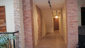A hallway with brick walls, a wooden door, and a staircase with a metal railing. - Cerca Hotel (Boracay Island)
