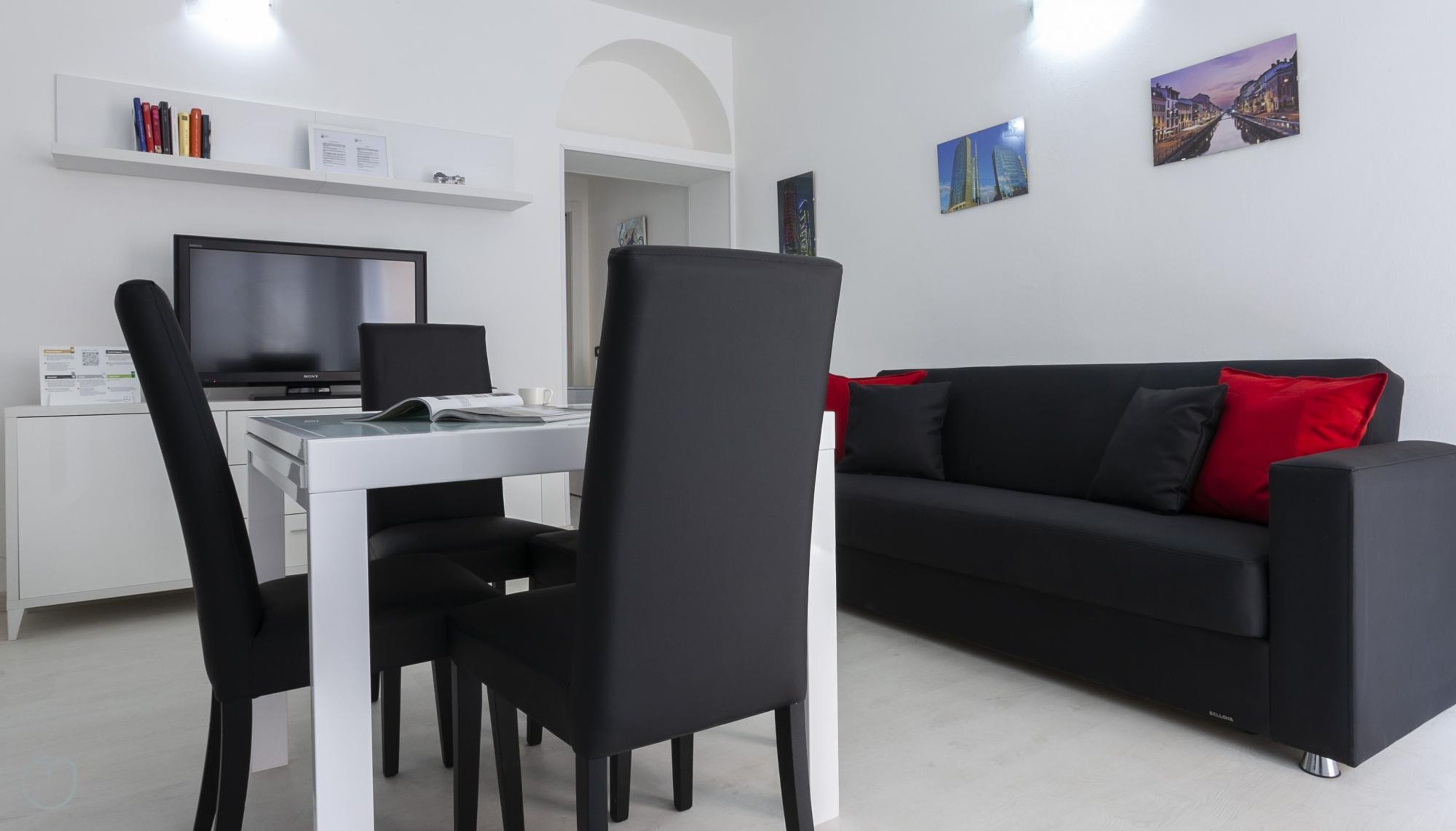 En moderne stue med en sort sofa, et hvidt skrivebord og et fladskærms-tv.