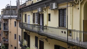 Un edificio a più piani con balconi, condizionatori d'aria e ringhiera metallica.