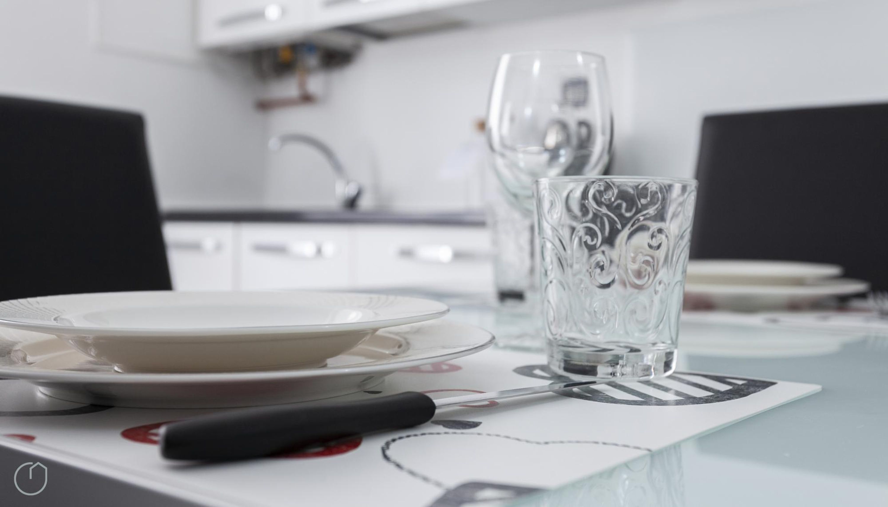 Une table à manger avec un set de table blanc orné d’un motif en forme de cœur, un verre et un couteau.