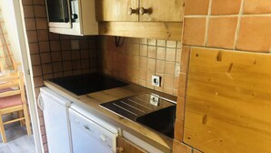 Pieni, käytännöllinen keittiö, jossa on valkoinen astianpesukone, musta liesi ja pesuallas.