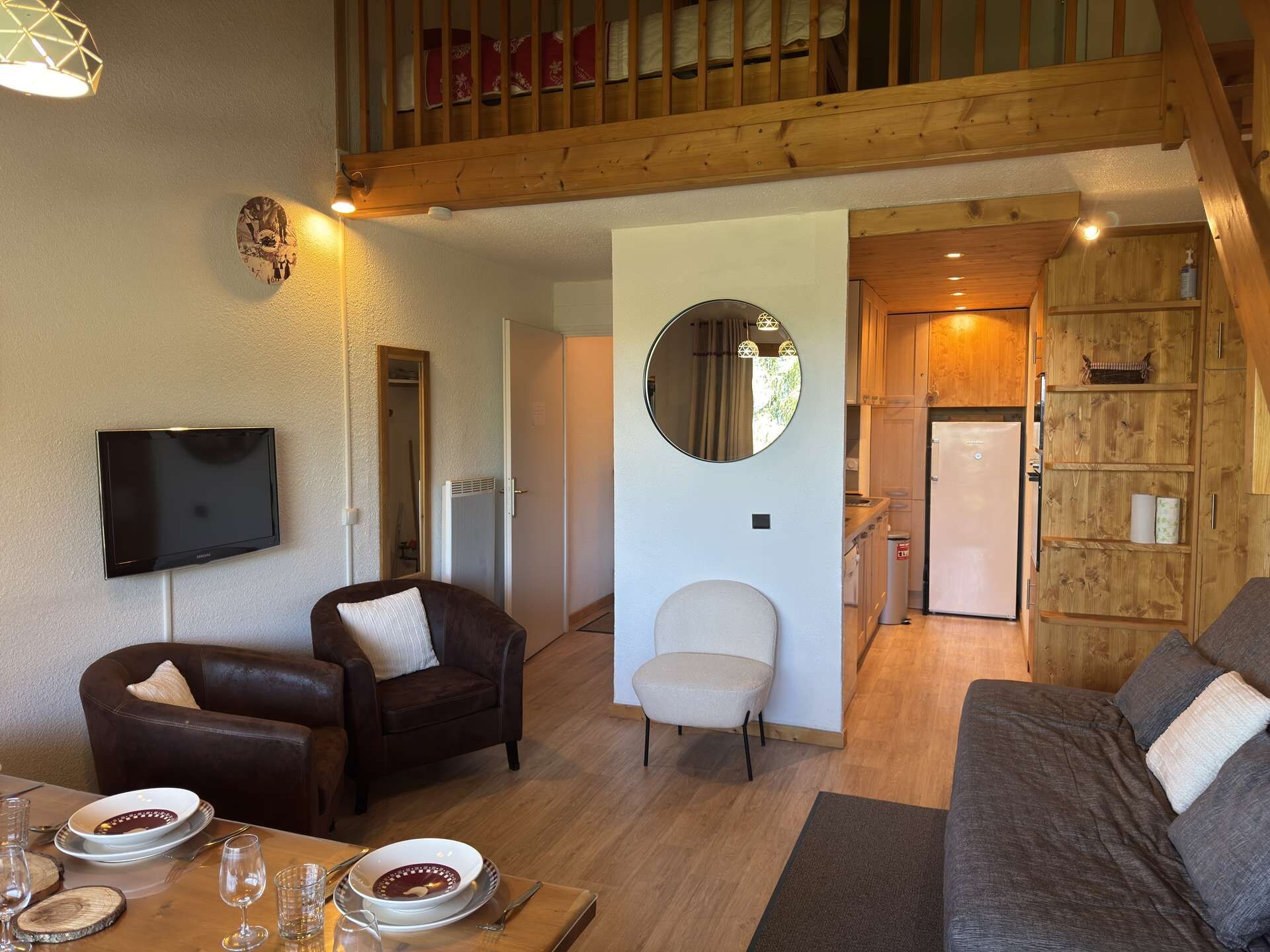 A cozy living room with a television, seating, and a dining area with a table set for two.