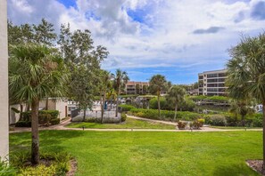 A well-maintained courtyard with a grassy lawn, palm trees, and a small water feature. - 2nd Floor, Beach Access, Heated Pool, Tennis/Pickleball, On Canal | Ready to Book! (Sarasota)