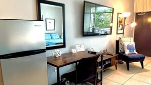 Cocina pequeña con refrigerador, una mesa de comedor y un banco.
