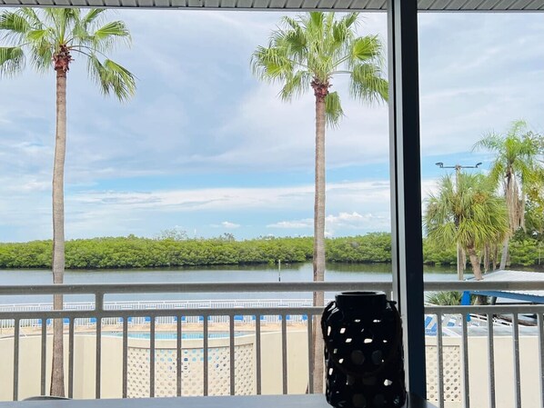 A balcony with a view of a beach, palm trees, and a body of water.