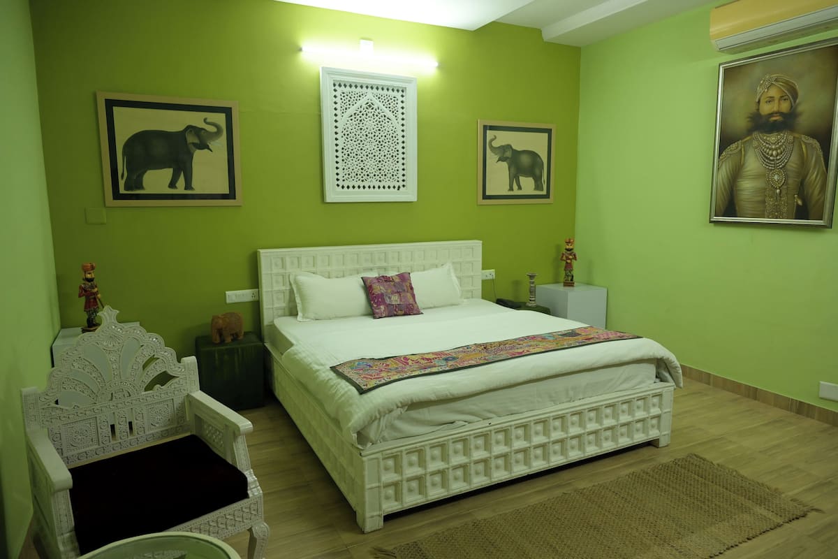 A room with a bed, a chair, and wall decorations including elephant and patterned designs.