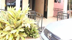 Un edificio con fachada curva, entrada protegida por un portón y un automóvil estacionado.
