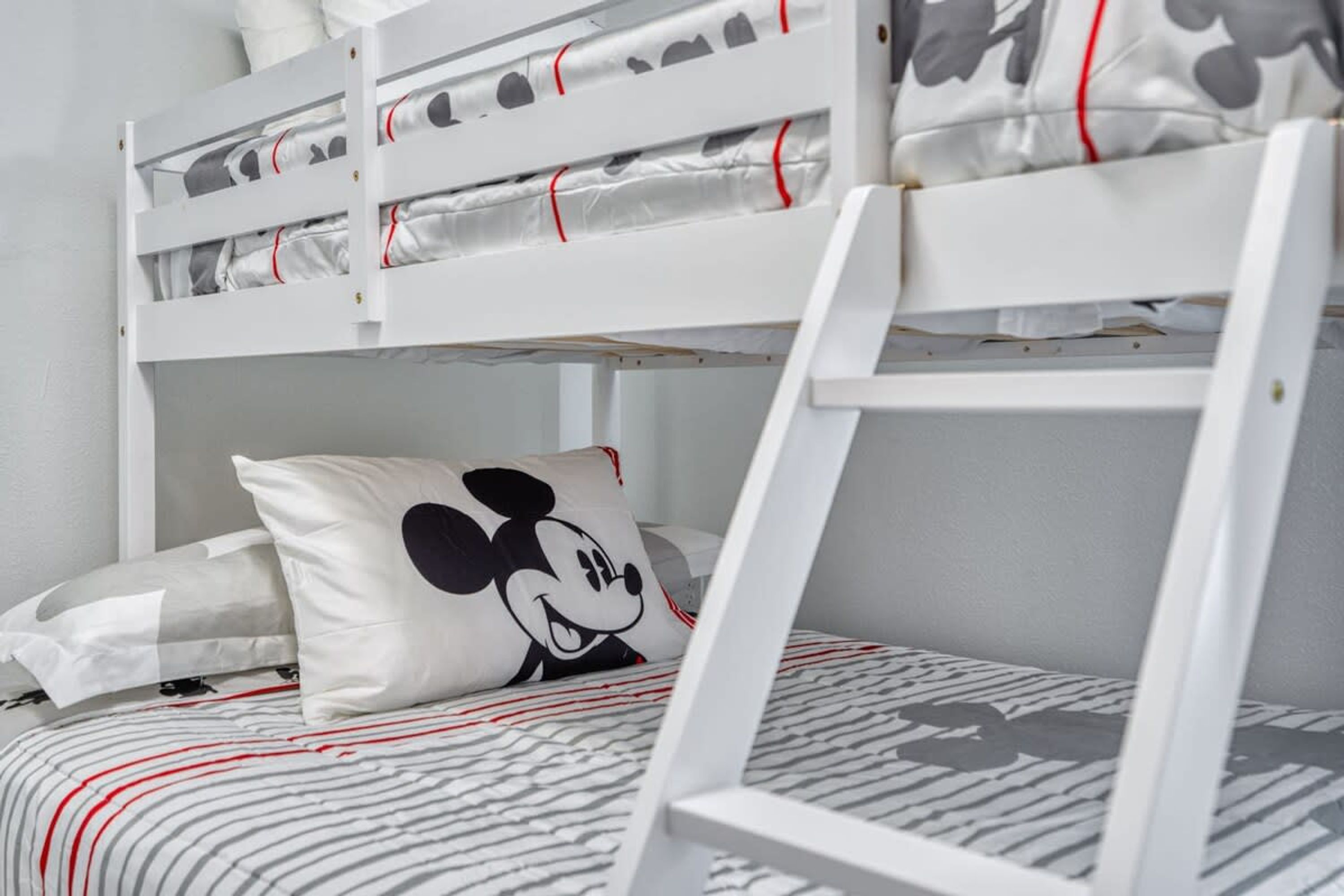 Un lit superposé avec un oreiller à l’effigie de Mickey Mouse et une parure de lit à rayures.