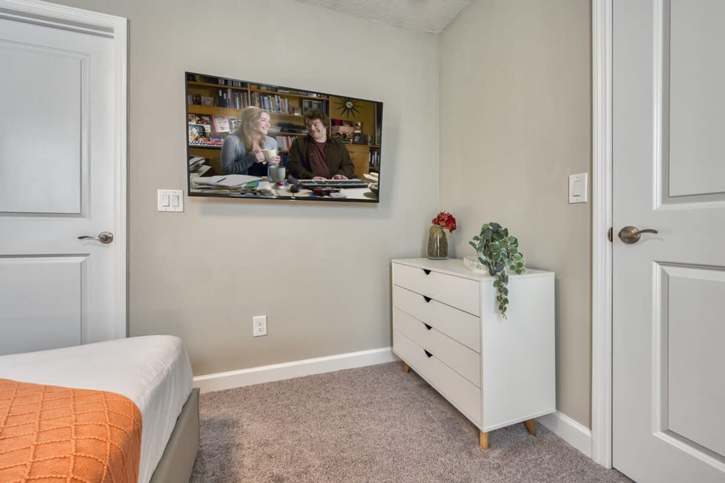A bedroom with a bed, a dresser, a mirror, and a wall-mounted picture.