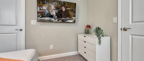 A bedroom with a bed, a dresser, a mirror, and a wall-mounted picture.