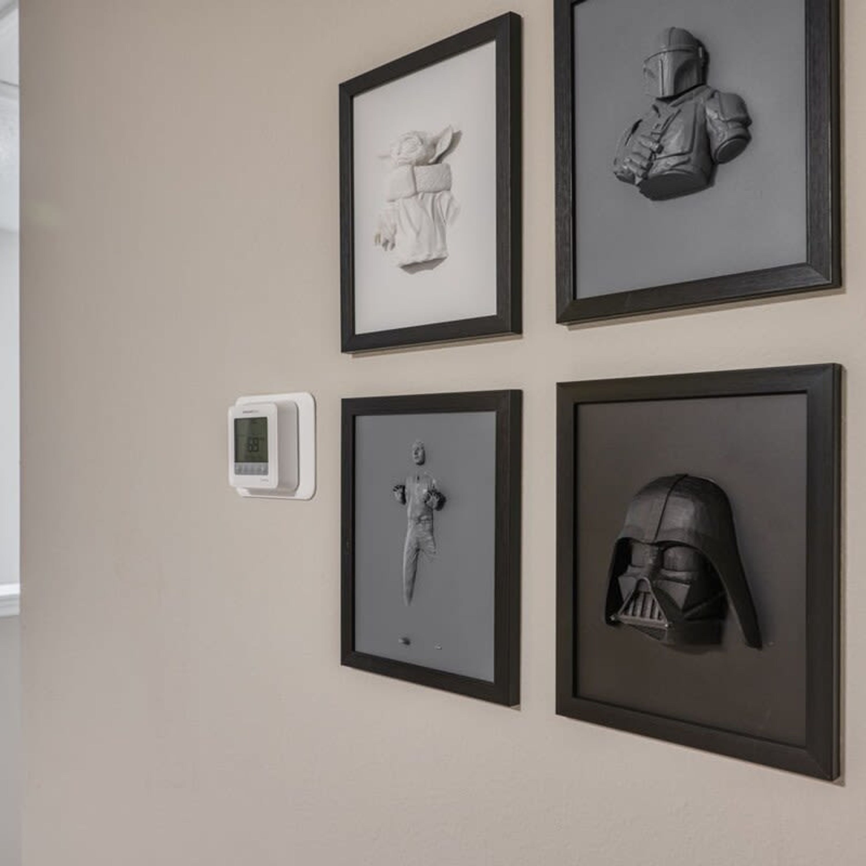 Quatre sculptures encadrées sont accrochées au mur, dont un casque et une figure tenant un bâton.