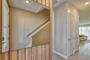 A modern interior with a wooden panel accent wall, a staircase, and a white door. - Luxury 5 Bedroom Home 10 Minutes From Disney (Kissimmee)