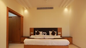 A modern bedroom with a large bed, wooden headboard, and a nightstand. - Hotel Ashok Palace (Manmangalam)