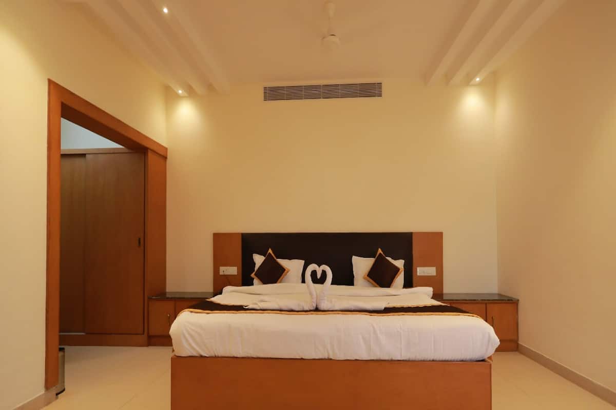 A modern bedroom with a large bed, wooden headboard, and a nightstand.