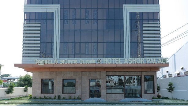 A hotel entrance with a modern design, featuring a large sign above the doors and a staircase leading up to the entrance. - Hotel Ashok Palace (Manmangalam)