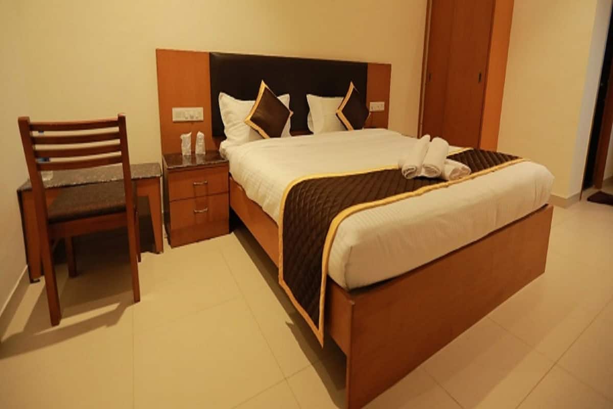 A hotel room with a bed, a wooden chair, a nightstand, and a wardrobe.