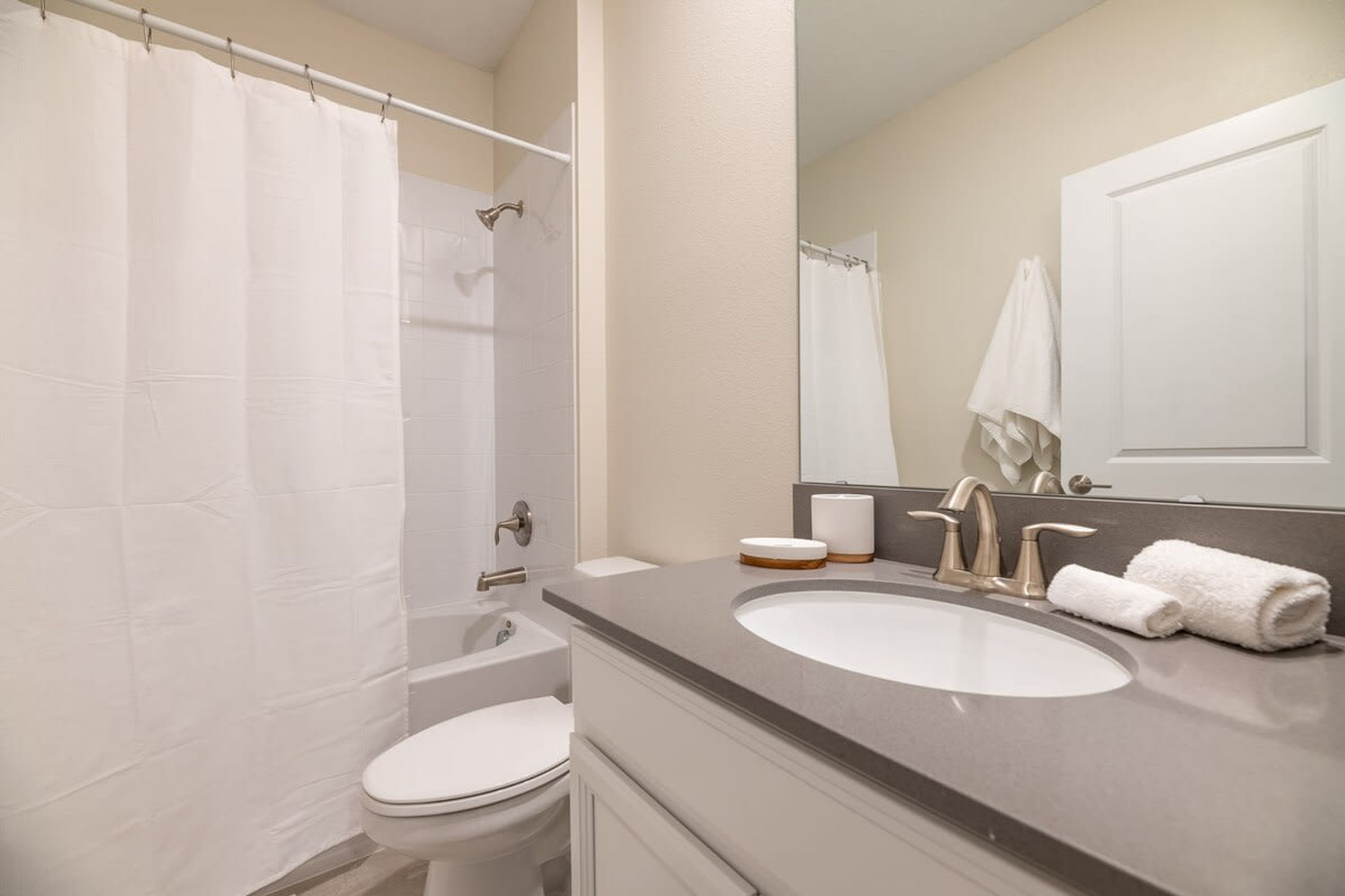 A bathroom with a white toilet, a sink with a mirror, and a shower curtain.