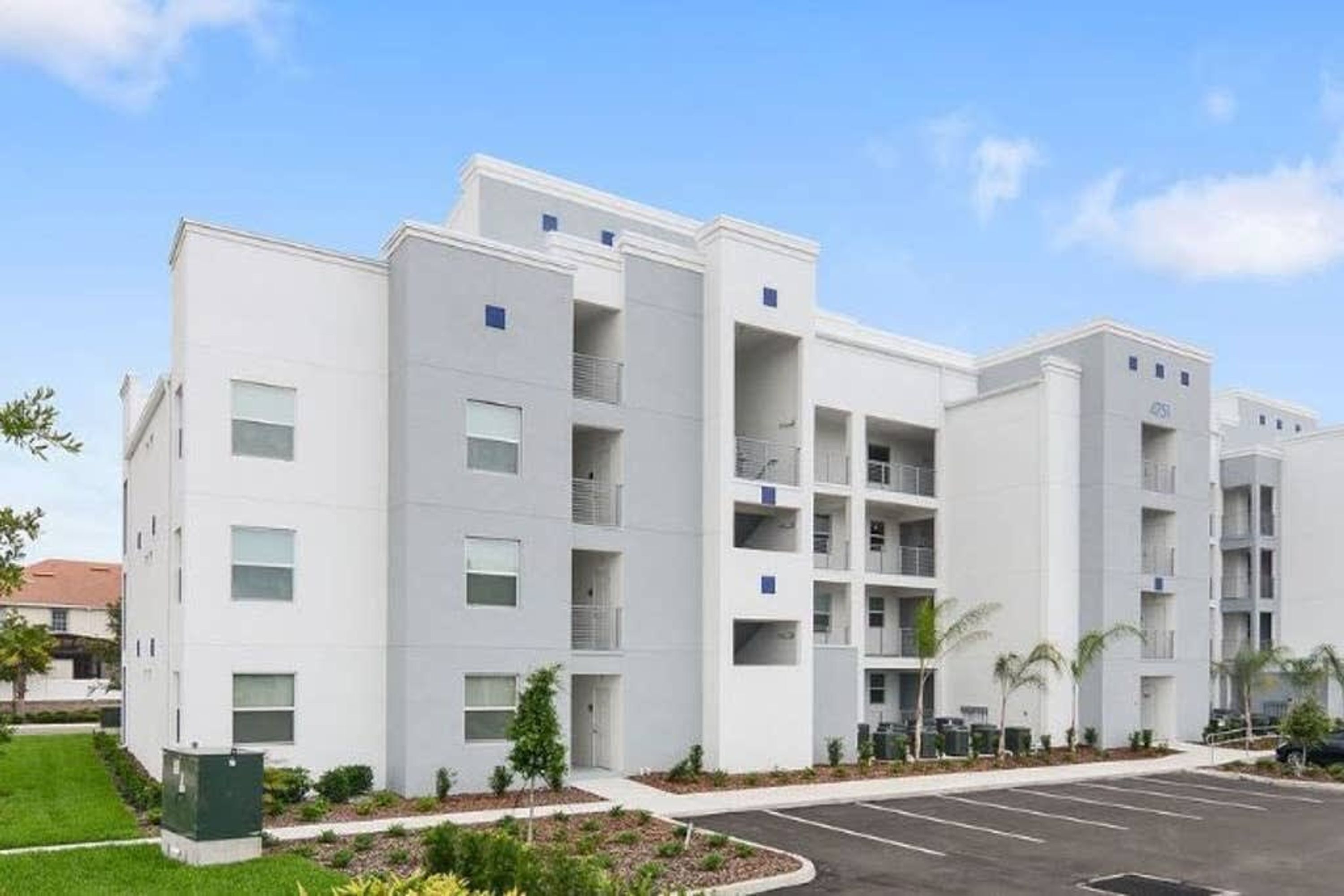 Un immeuble moderne à plusieurs étages, avec un parking situé devant.