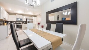 A modern kitchen with white cabinets, a central island, and stainless steel appliances. - 3BR Apartment - Great Location Super Comfort (Kissimmee)