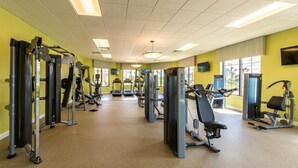 A gym with various exercise machines, a treadmill, and a television on the wall.