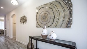 A hallway with a dark console table, two decorative vases, and a large circular wall art piece.