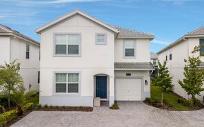 Ein zweigeschossiges Wohnhaus mit Garage, einer blauen Tür und einer kleinen Veranda.
