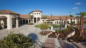 A courtyard with a central fountain, palm trees, and a covered seating area.
