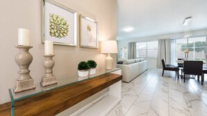 A modern living room with a glass coffee table, a sofa, and a dining area with a table and chairs.