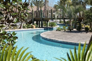 A swimming pool with a curved edge, surrounded by palm trees and a wooden bridge. - Private Pool Modern Elegance Ideal Locale (Davenport)