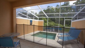 A covered outdoor pool area with a glass enclosure, a hot tub, and two lounge chairs. - Charming Cozy Haven in Four Corners (Clermont)