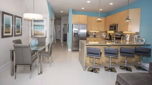 A modern kitchen with a central island, stainless steel appliances, and bar stools. - Charming Cozy Haven in Four Corners (Clermont)