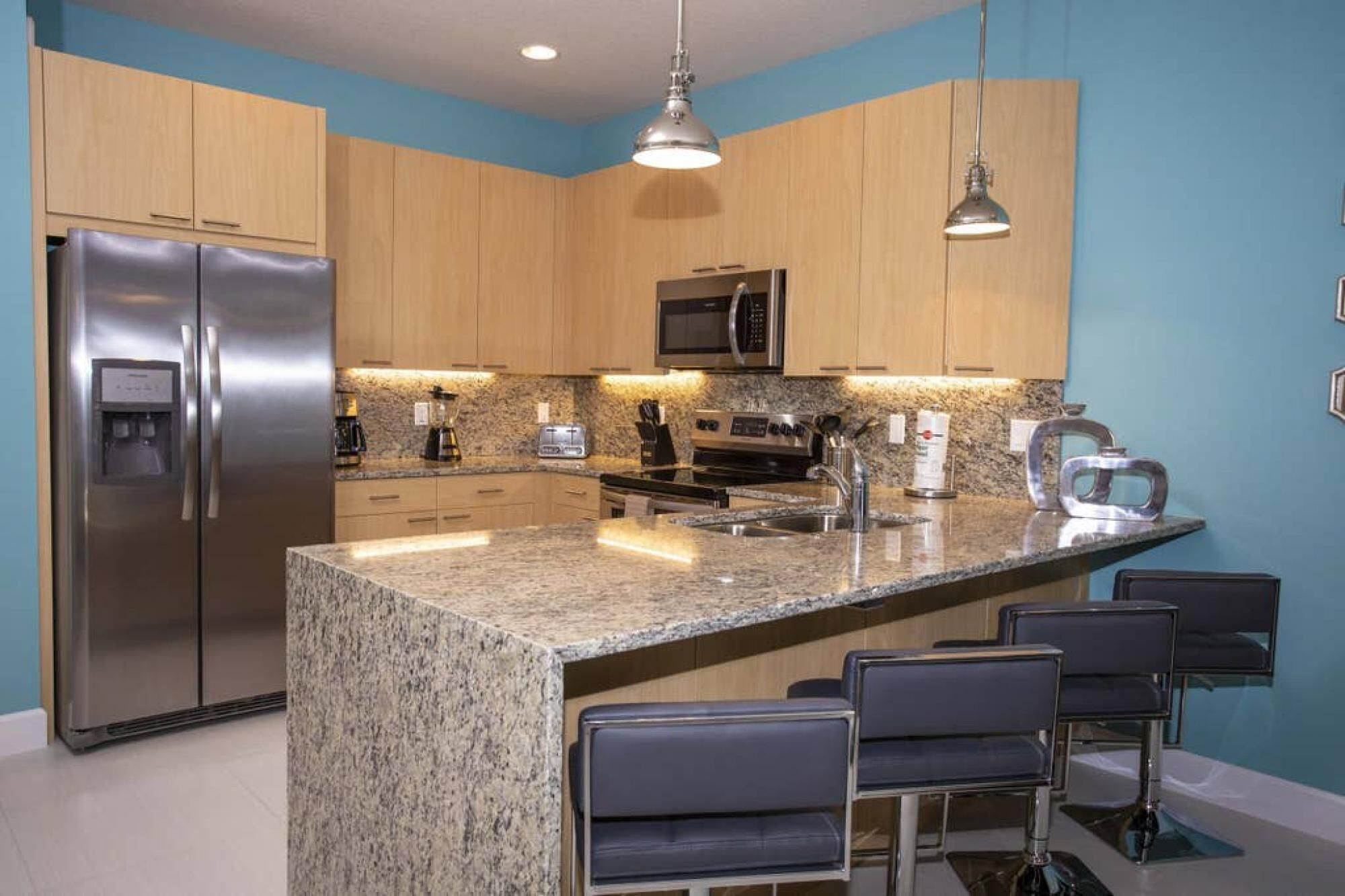 A modern kitchen with granite countertops, stainless steel appliances, and a central island with bar stools.