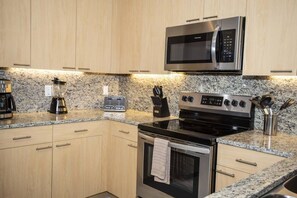 A modern kitchen with granite countertops, stainless steel appliances, and wooden cabinets. - Charming Cozy Haven in Four Corners (Clermont)