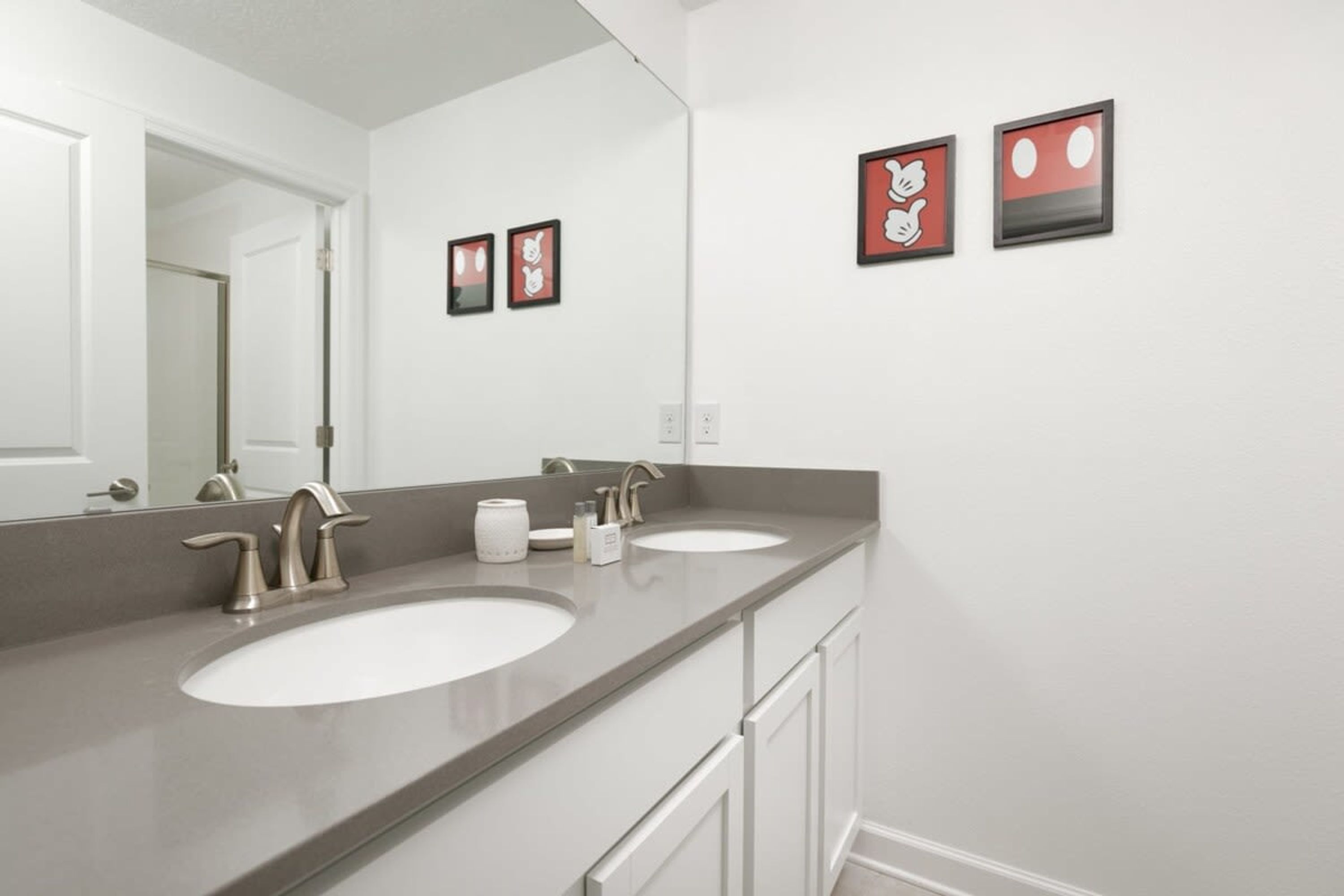 A bathroom with two sinks, a large mirror, and framed artwork on the wall.