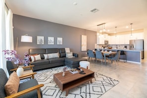 A modern living room with a sofa, coffee table, and artwork on the wall. - Chic Spacious Condo for the Best Vacations (Davenport)