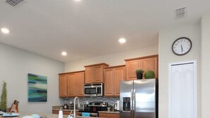 A modern kitchen with granite countertops, stainless steel appliances, and wooden cabinets. - Charming 4 BDR Townhome at Storey Lake Resort (Kissimmee)
