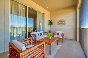 A balcony with a wooden table, two chairs, and a sofa.